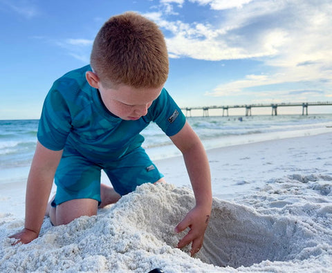 Child playing in white sand at the beach for stunning beach photos with iPhone.