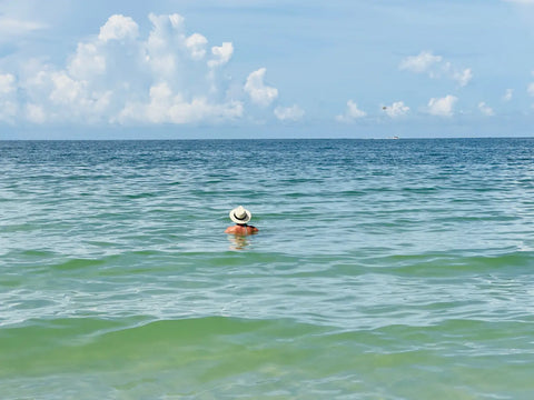 Person in sun hat floating in turquoise water for stunning beach photos with iPhone.